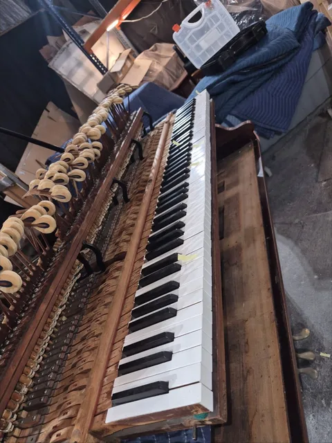 Exposed grand piano action and keyboard on a padded work area