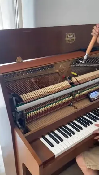 Tuning lever fitted to an open upright piano with the action and keyboard exposed